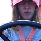 photo showing a girl wearing an old fashioned pink bonnet with a steering wheel in front of her at the Kutztown Festival 